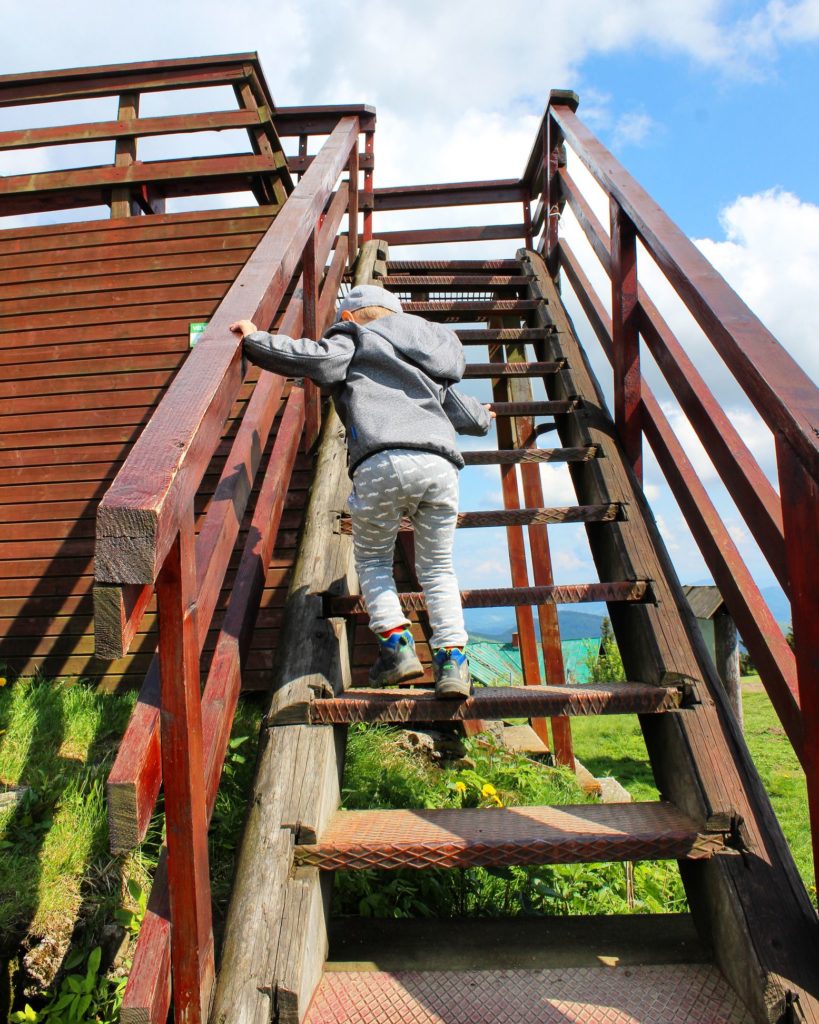 Dziecko wchodzące na strome schodki prowadzące na platformę widokową na Wielkiej Raczy
