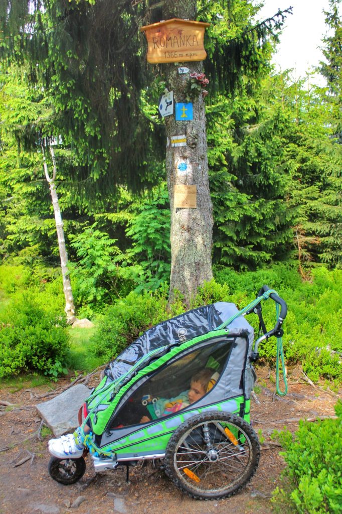 Romanka z dzieckiem w wózku, wózek zaparkowany pod drzewem z tabliczką Romanka