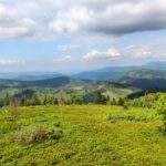 krjobraz na góry widziany ze slowackiego szczytu Wielka Racza, niebo pokryte obłokami, zielona trawa