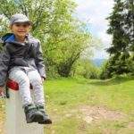 uśmiechnięte dziecko siedzące na słpku granicznym na szczycie Kikula