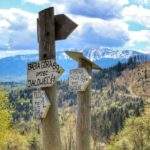 Drewniane słupy z drogowskazami na tle Babiej Góry przy schronisku W Murowanej Piwnicy w Zawoi