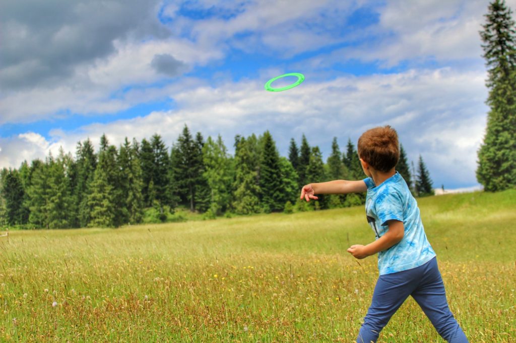 Dziecko rzycające frisbee na polanie w Pieninach