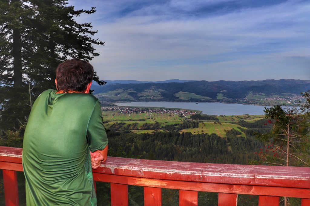 Turysta podziwiający widoki rozciągające się z wiezy widokowej na górze Żar w Pieninach, widok między innymi na Jezioro Czorsztyńskie oraz Gorce