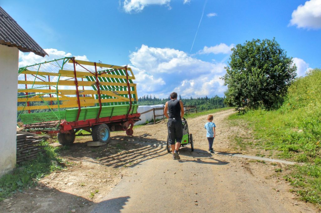 Turysta z dzieckiem i wózkiem idący szeroką drogą, Falsztyn
