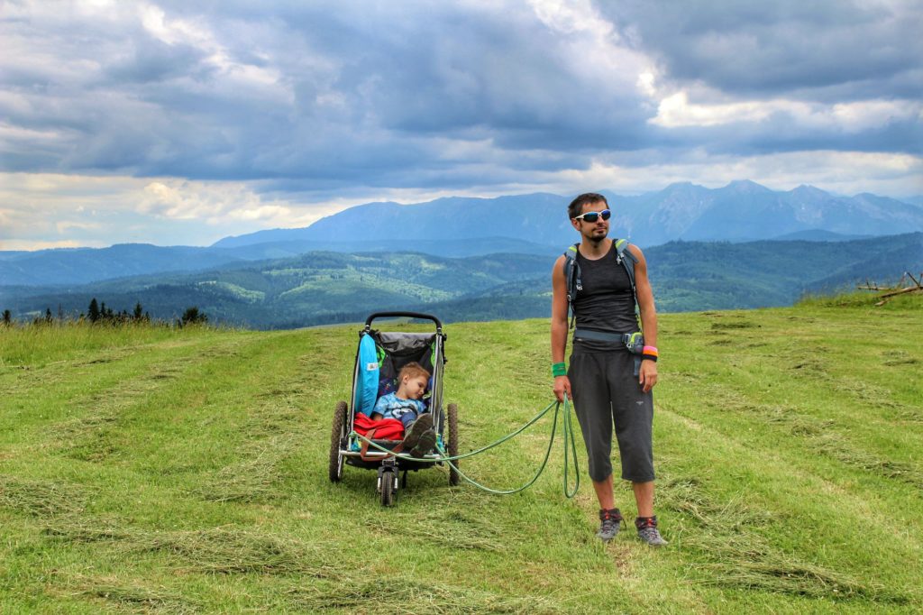 Turysta z dzieckiem w wózku na polanie w Pieninach, widok górski