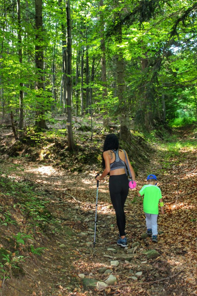 Turystka idąca z dzieckiem leśną ścieżką