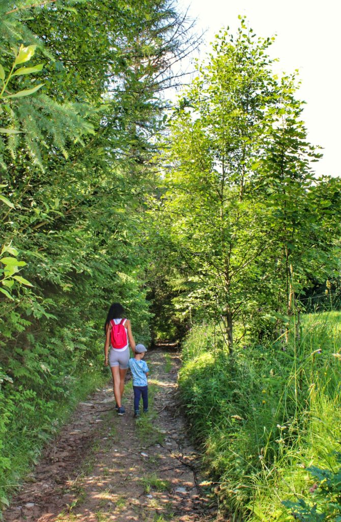 Turystka idąca z dzieckiem leśną drogą