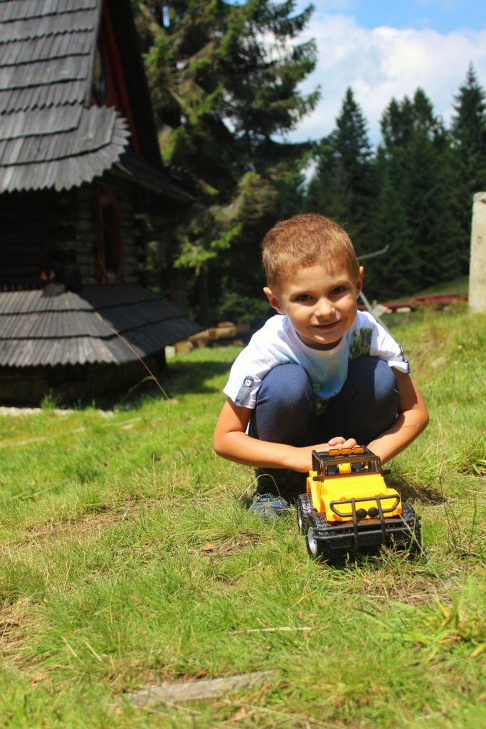Dziecko bawiące się żółtym samochodem na Polanie Rusnakowej w Gorcach