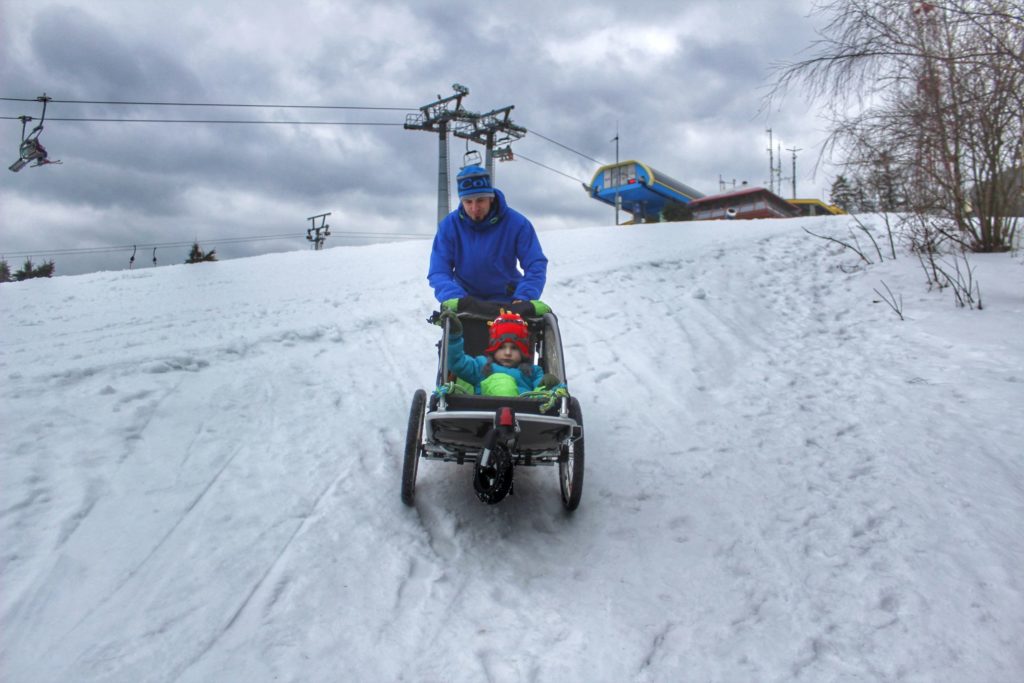 Turysta zjeżdżający z dzieckiem w wózku ze szczytu Czantoria, widoczny wyciąg na Czantorii, zimowa pora
