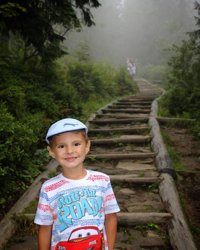 Uśmiechnięte dziecko na kamienno - drewnianej ścieżce na szlaku idącym na Babią Górę