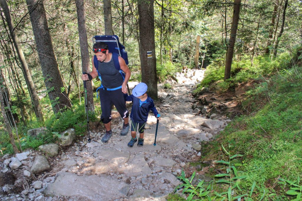 Turysta z dzieckiem pokonujący strome, kamieniste podejście w Tatrach Słowackich