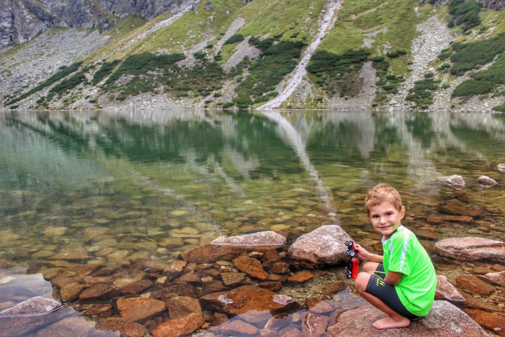 Uśmiechnięte dziecko kucające na skale przy Czarnym Stawie Gąsienicowym w Tatrach Wysokich