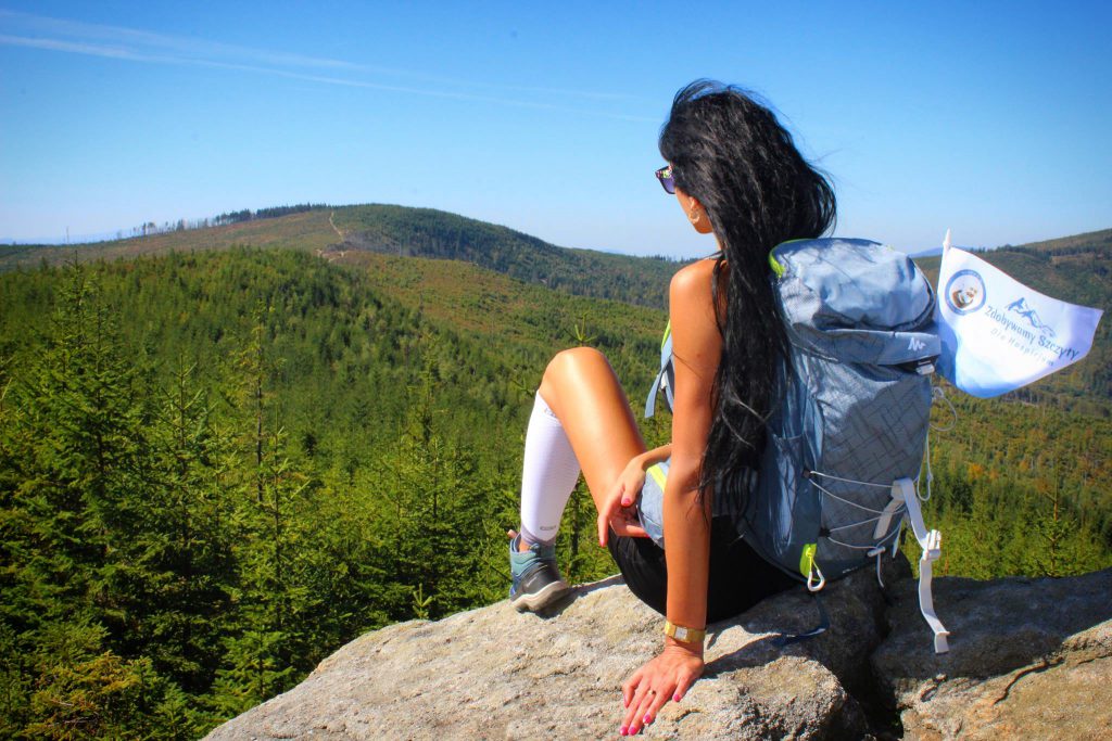 Kobieta na Magurce Radziechowskiej siedząca tyłem na skale, patrząca na krajobraz górski 