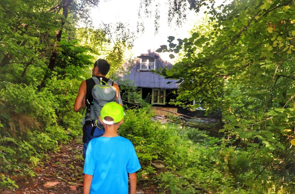 Leśna ścieżka, drewniana chatka na czarnym szlaku idącym z Kozubnika, turysta z dzieckiem