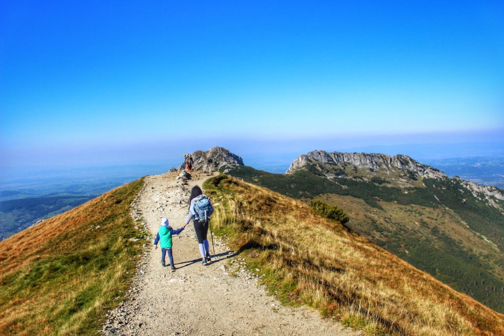 Turystka z dzieckiem idąca w kierunku Kondrackiej Przełęczy, widok na Giewont
