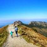 Turystka z dzieckiem idąca w kierunku Kondrackiej Przełęczy, widok na Giewont
