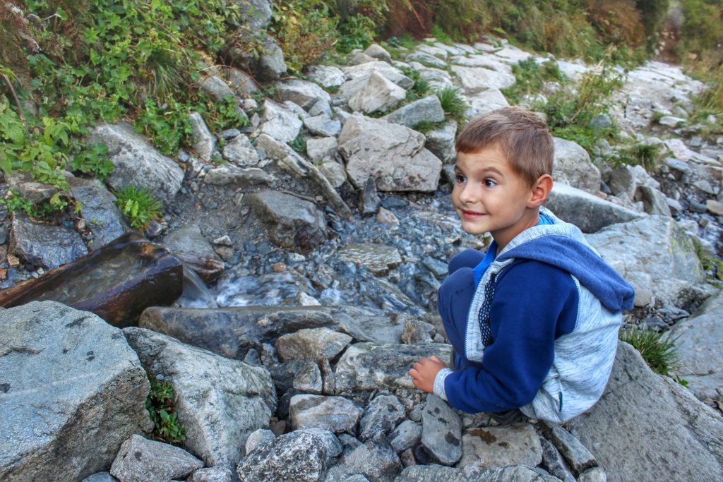 Uśmiechnięte dziecko przy potoku górskim, teren tatrzańskiego parku narodowego
