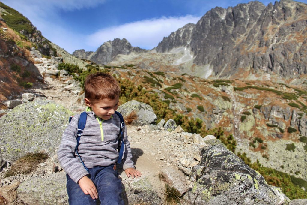 Mały, dzielny turysta siedzący na skale pod szczytem Gerlach