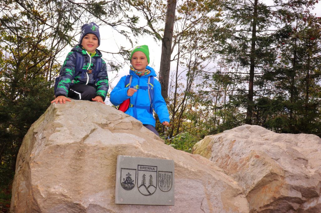 Sześcioletnie dzieci stojące na skale z tabliczką BRENNA na Trzech Kopcach Wiślańskich
