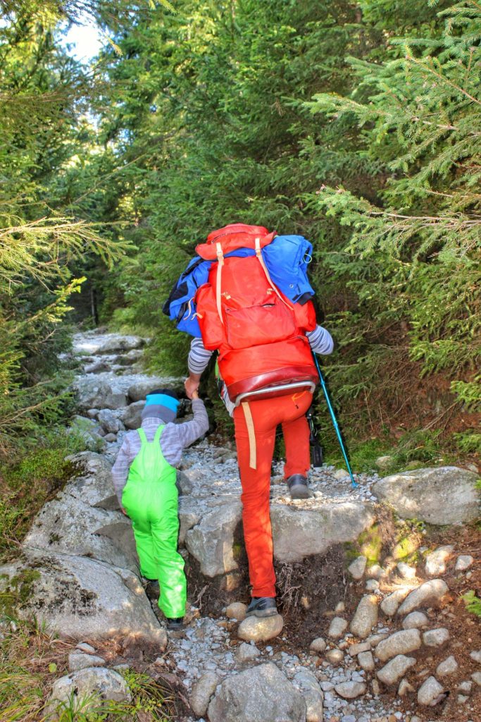 Turysta z dzieckiem na kamienistym szlaku w Tatrach Wysokich