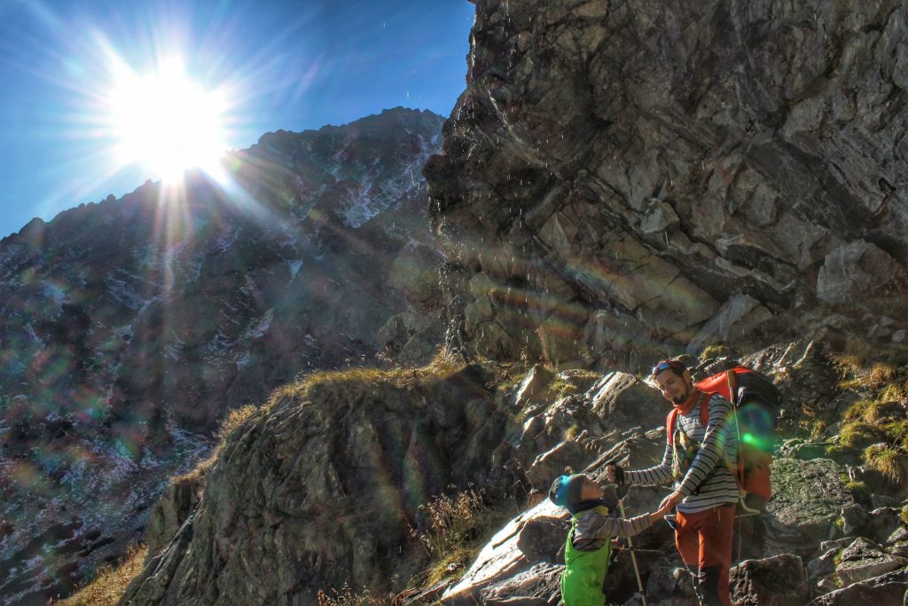 Turysta z dzieckiem na szlaku w Tatrach Wysokich - Dolina Wielicka, skały, z których kapie woda, słońce