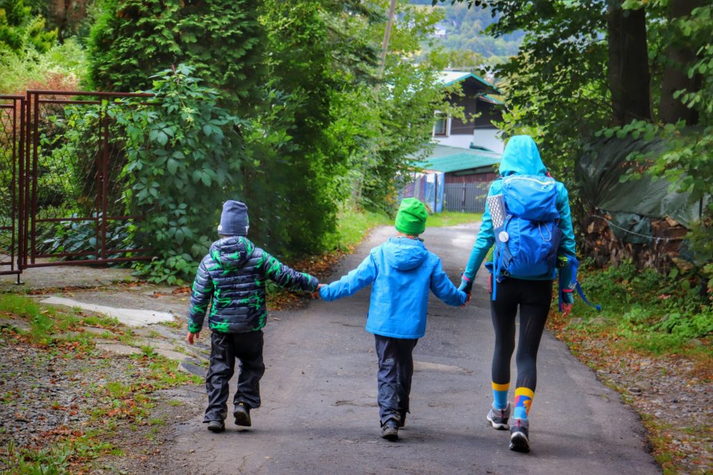 Turystka idąca z dziećmi asfaltową drogą w Wiśle