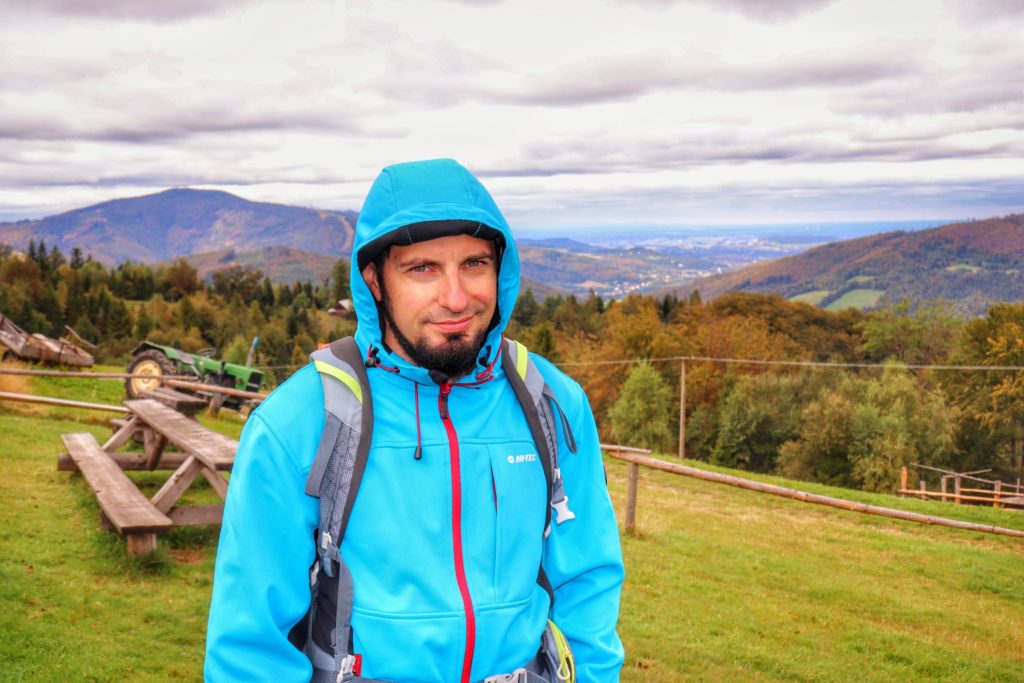 Zakapturzony turysta na Trzech Kopcach Wiślańskich, w tle krajobraz górski