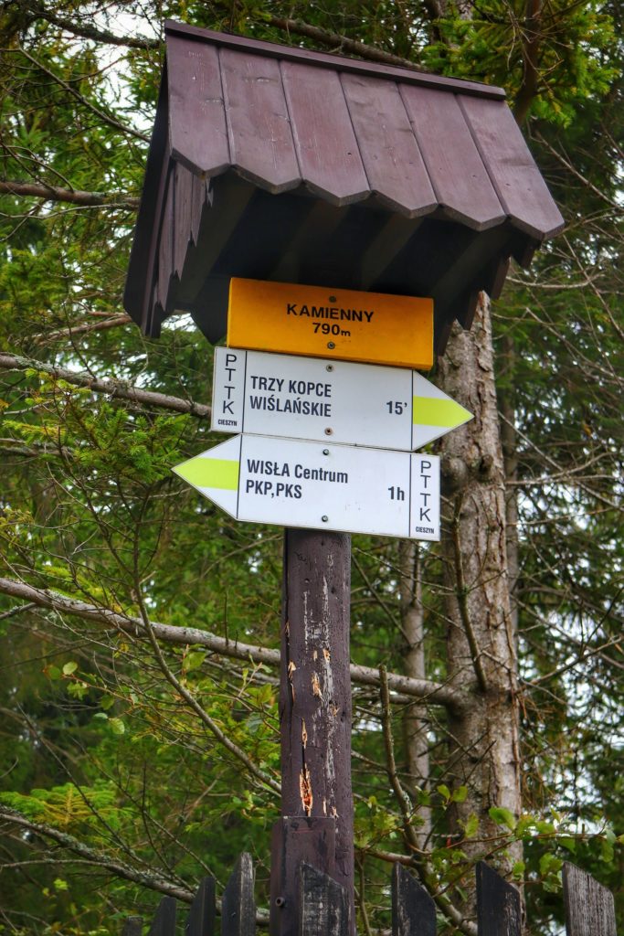 Żółta tabliczka z napisem Kamienny 790 m, szlak żółty na Trzy Kopce Wiślańskie 15 minut