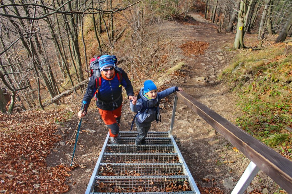 Mężczyzna z dzieckiem wchodzący pod metalowe schody, jesienny dzień, szlak na Wysoką