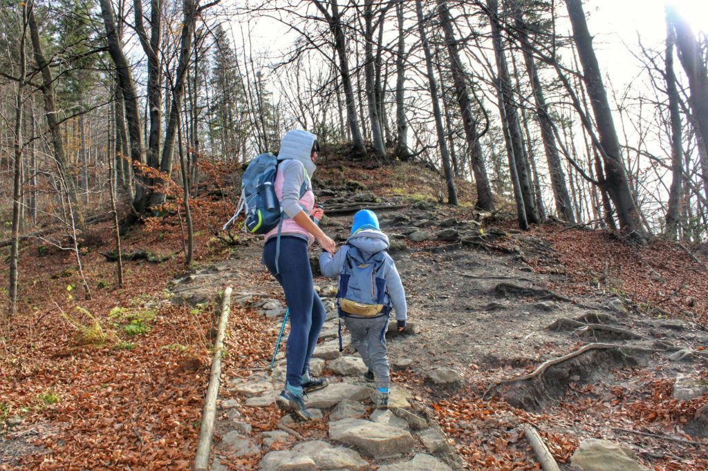 Turystka z dzieckiem wchodząca kamienitą ścieżką w kierunku szczytu Wysoka, chłodny, jesienny dzień