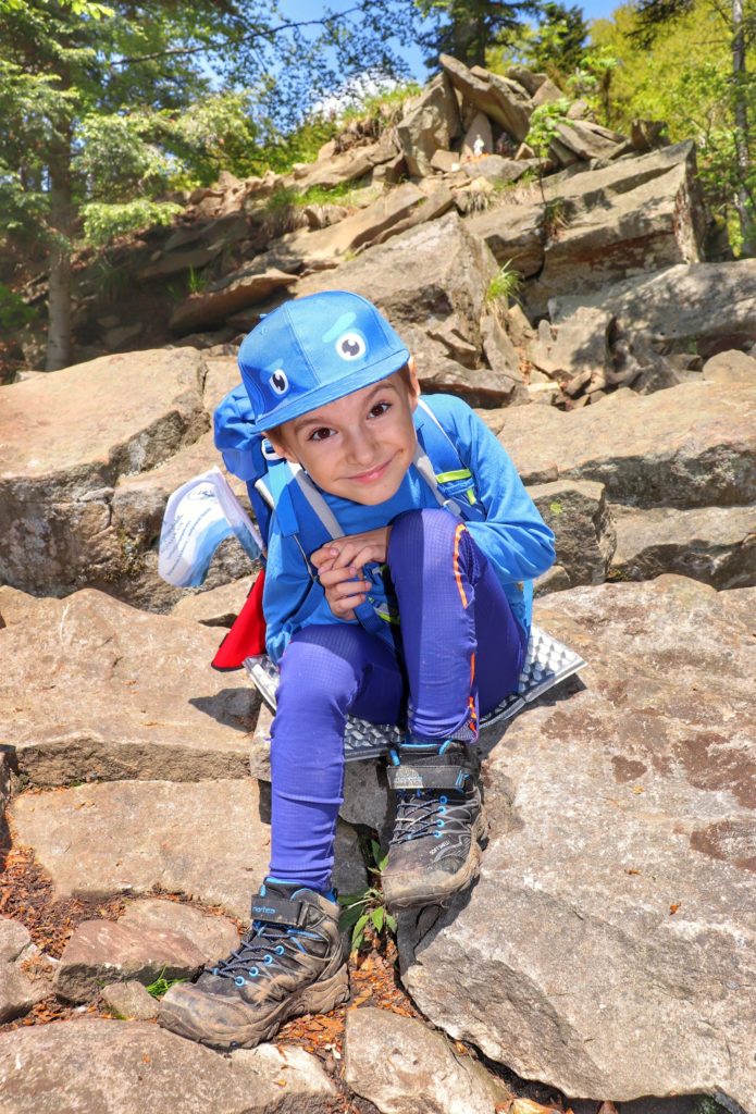 Uśmiechnięte dziecko odpoczywające na skałach - Perć Borkowskiego na żółtym szlaku na Luboń Wielki