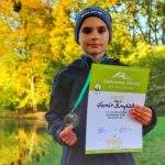 Dziecko trzymające dyplom oraz medal zdobyty w akcji zdobywamy szczyty dla hospicjum, jesienny park w Pszczynie