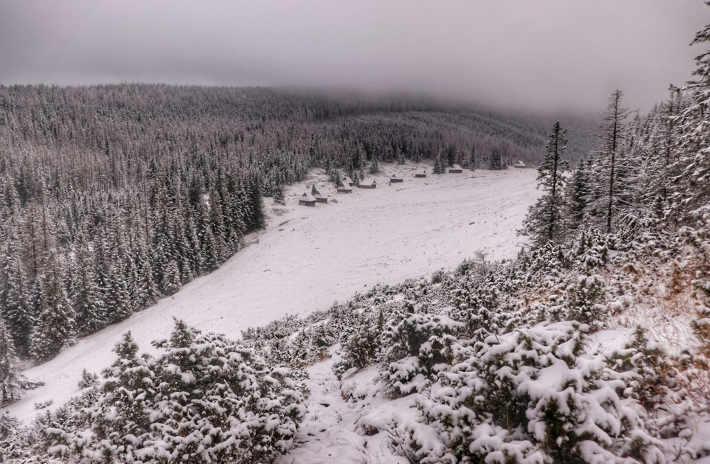 Polana Kopieniec zimą widziana z góry, szałasy pasterskie, drzewa zaśnieżone, gęsta mgła w oddali