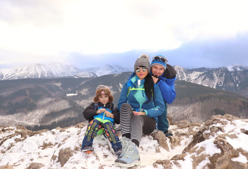 Rodzina trzyosobowa z dzieckiem odpoczywająca na szczycie Nosal, w tle ośnieżone Tatry