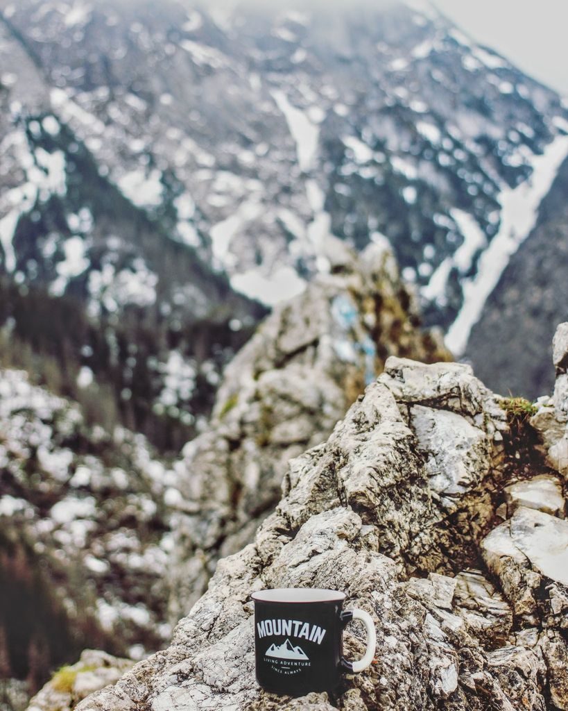 Czarno biały kubek z napisem MOUNTAIN leżący na skałach, w tle Tatrzański szczyt