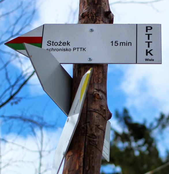 Drewniany słup z drogowskazem (czerwono, zielony szlak) informującym, że za 15 minut dojdzie się do Schroniska PTTK na Wielkim Stożku