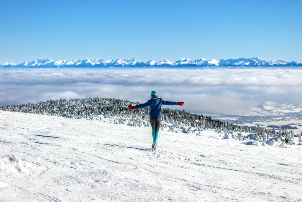 Kobieta na zaśnieżonym Pilsku, radośnie biegnąca w stronę morza mgieł oraz Tatr