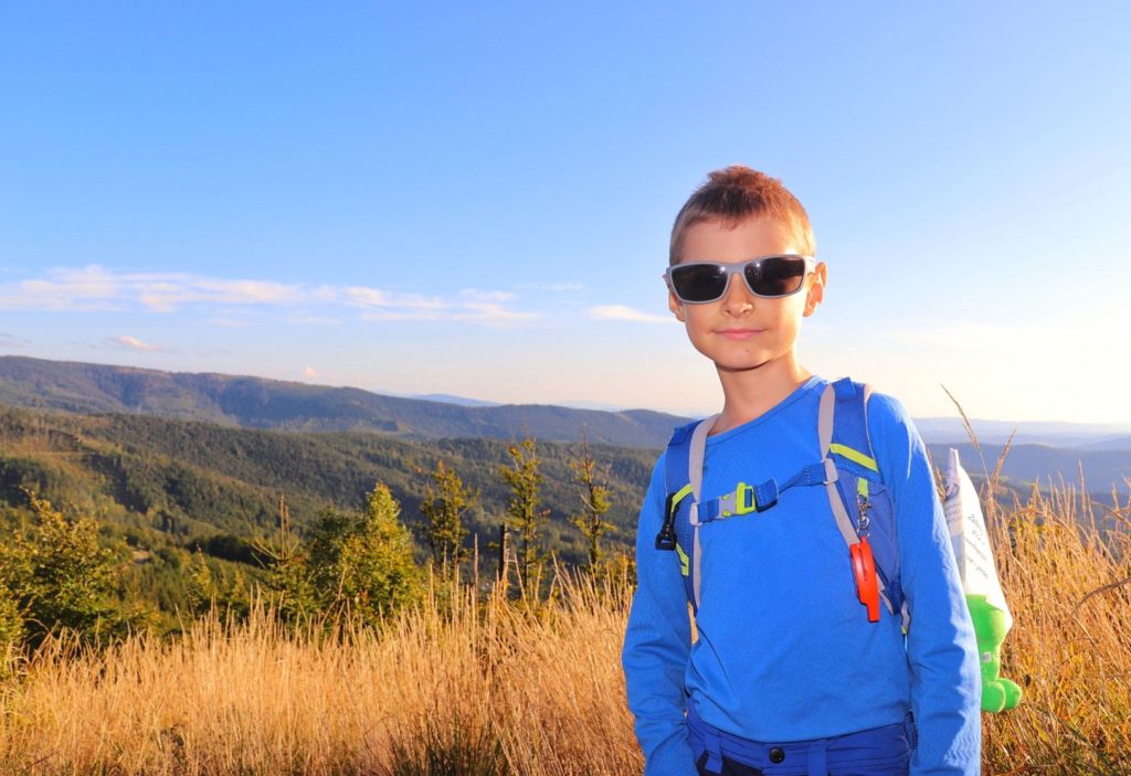 Uśmiechnięte dziecko na czerwonym szlaku idącym na Malinowską Skałę w Beskidzie Śląskim, letni słoneczny dzień, błękitne niebo