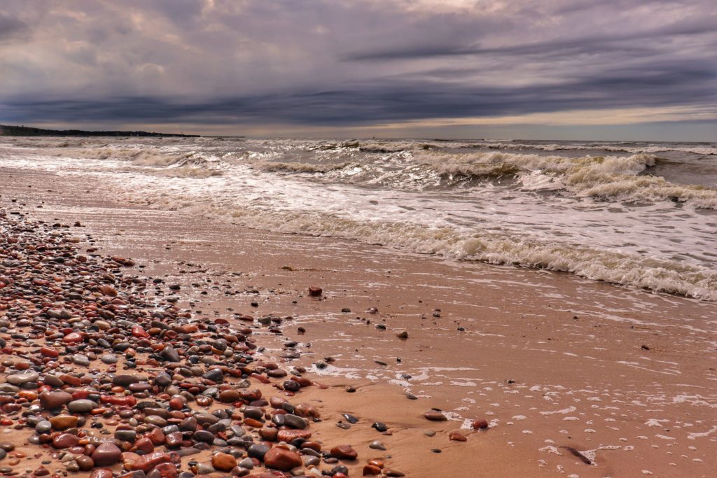 Widok na morze Bałtyckie z plaży w Orzechowie koło Ustki, piasek, kamienie, pochmurny, letni dzień