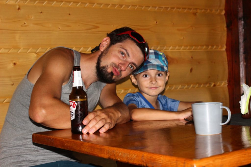 Mężczyzna z chłopcem siedzi przy drewnianym stole w schronisku na Wielkiej Raczy