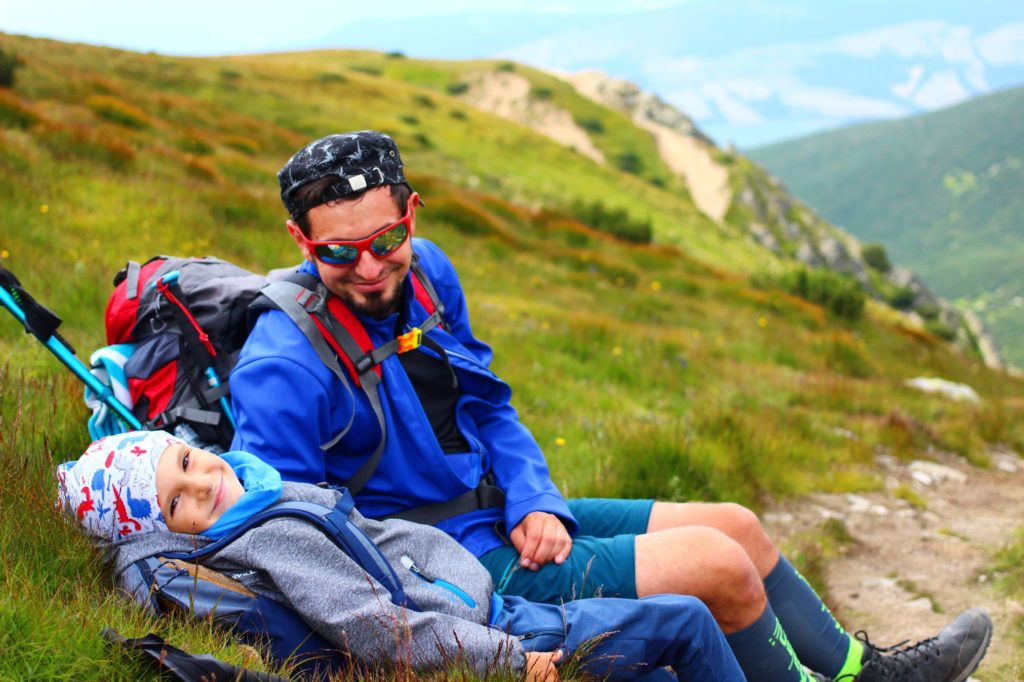 Szczęśliwy mężczyzna z dzieckiem odpoczywający na trawie w Tatrach Słowackich