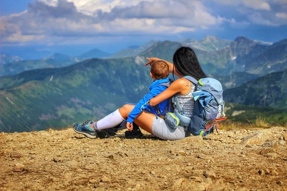 Turystka siedząca z dzieckiem na kamieniach, pokazująca maluchowi tatrzańskie szczyty w drodze na szczyt Salatyn