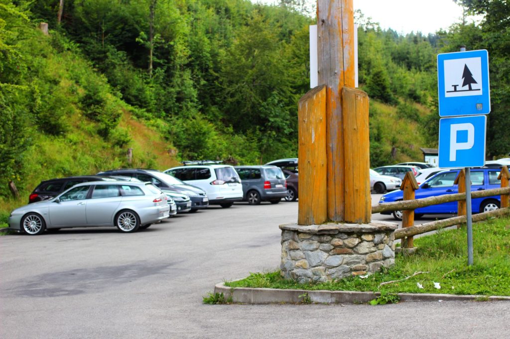 Zapełniony parking leśny pod Raczą, znaki drogowe informujące o parkingu