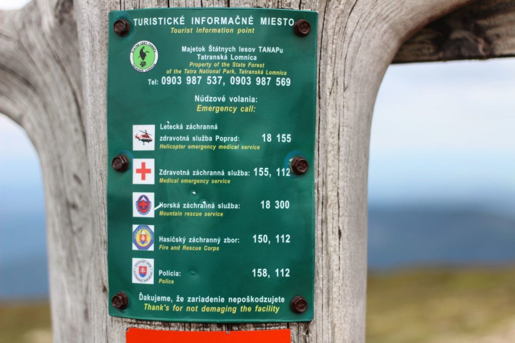 Zielona tablica informacyjna z numerami kontaktowymi do słowackich służb