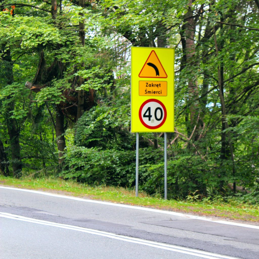 żółty znak ostrzegający przed ostrym Zakrętem Śmierci oraz o ograniczeniu prędkości do czterdziestu