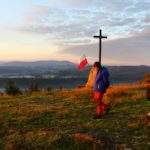 mężczyzna z dzieckiem przechadzający się po szczycie Koczy Zamek, pomnik i krzyż na Koczym Zamku, widoki górskie, oświetlone przez wschodzące słońce