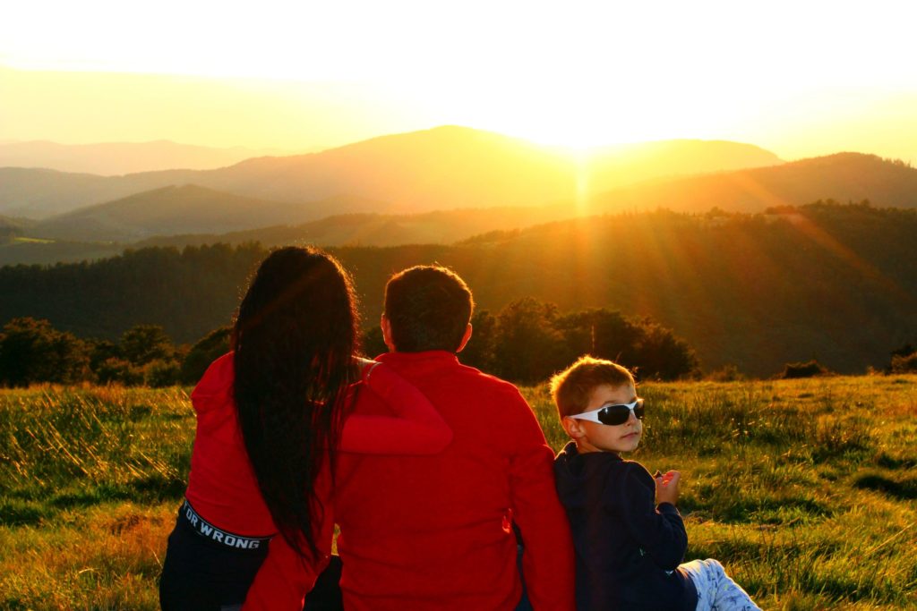rodzina siedząca na Hali Jaworowej, podziwiająca zachodzące słońce, chowające się za górami
