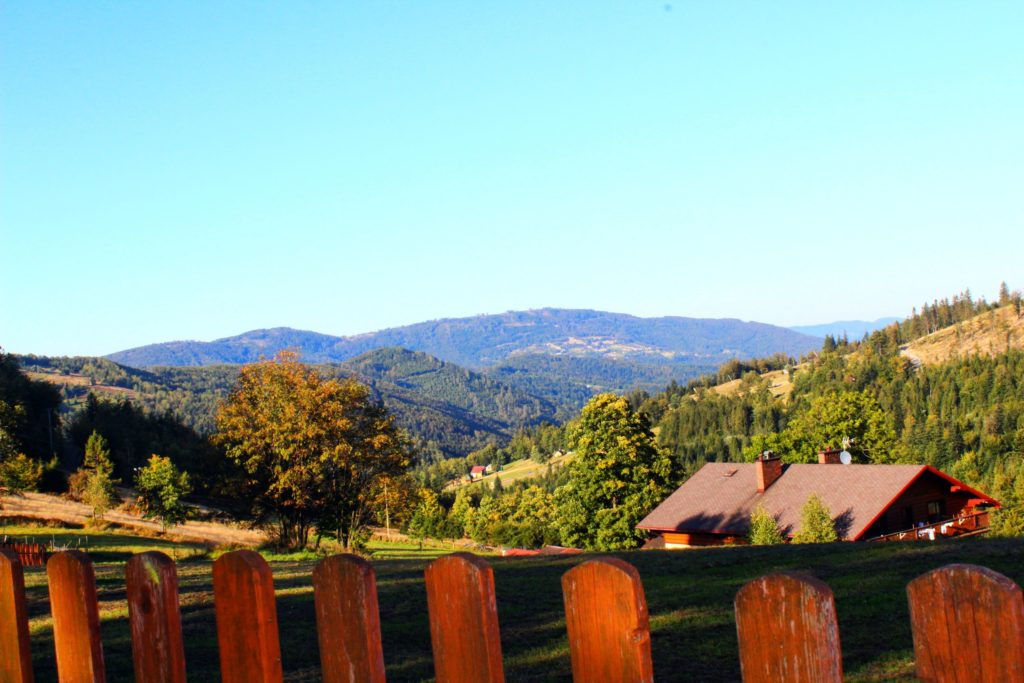 widok z Przełęczy Salmopolskiej w kierunku wyciągu Biały Krzyż, widoczne pobliskie pasma górskie oraz domy
