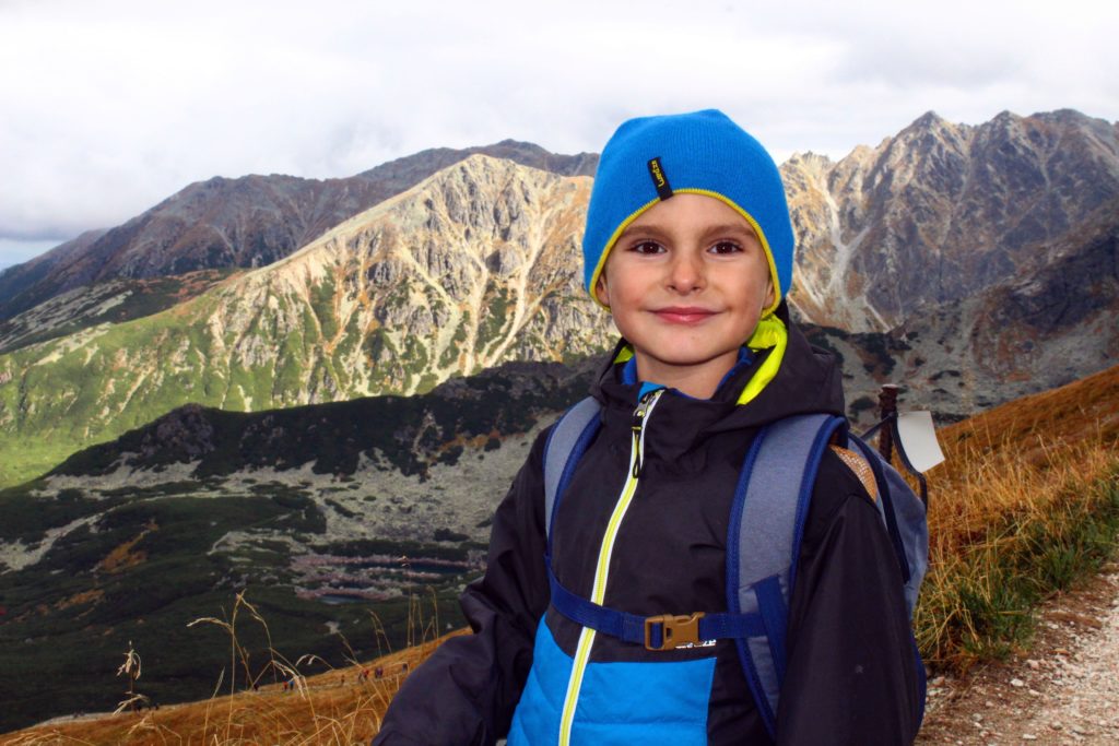 zadowolone dziecko na szczycie Kasprowy Wierch na tle tatrzańskich szczytów