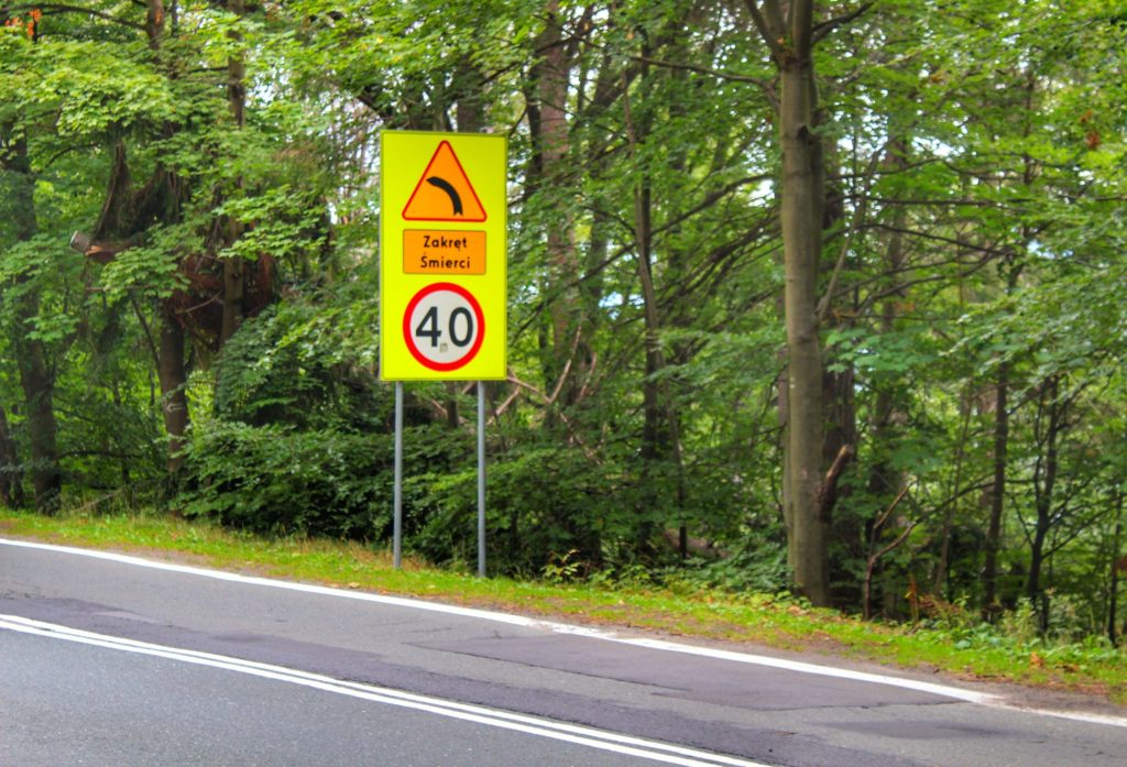 Żółty znak ostrzegający przed ostrym Zakrętem Śmierci w Szklarskiej Porębie oraz o ograniczeniu prędkości do czterdziestu